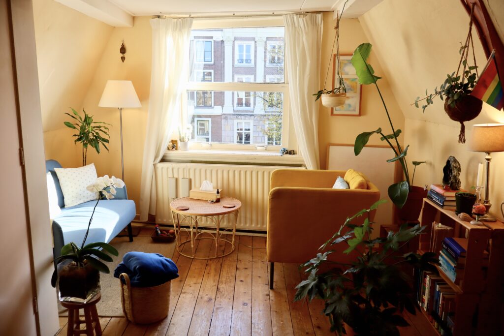 A warm, plant-filled therapy room with armchairs and natural window light